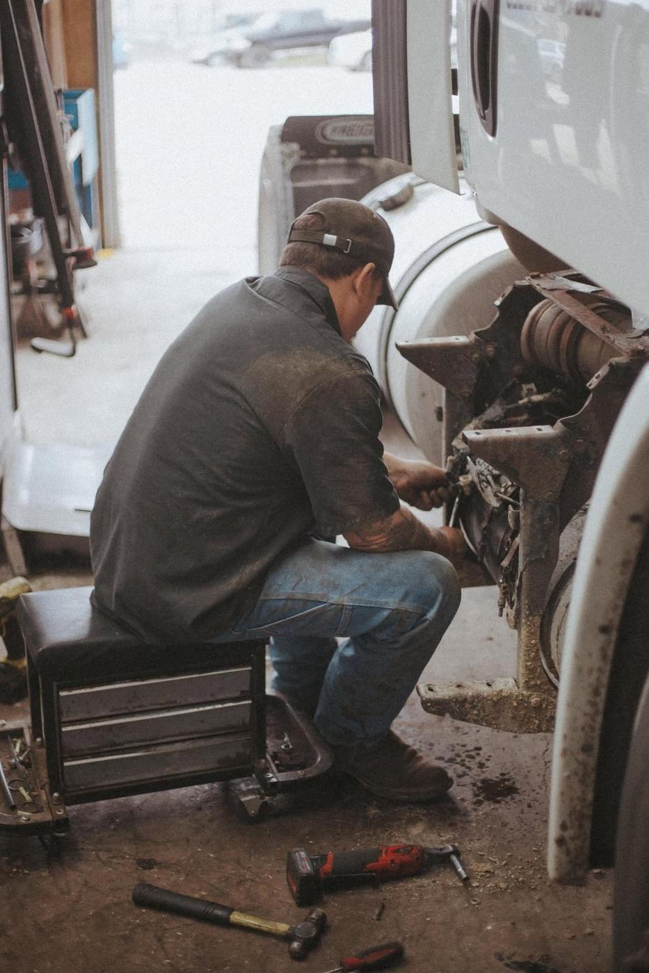 A T&T mechanic working at the front axle of a white semi tractor in the shop