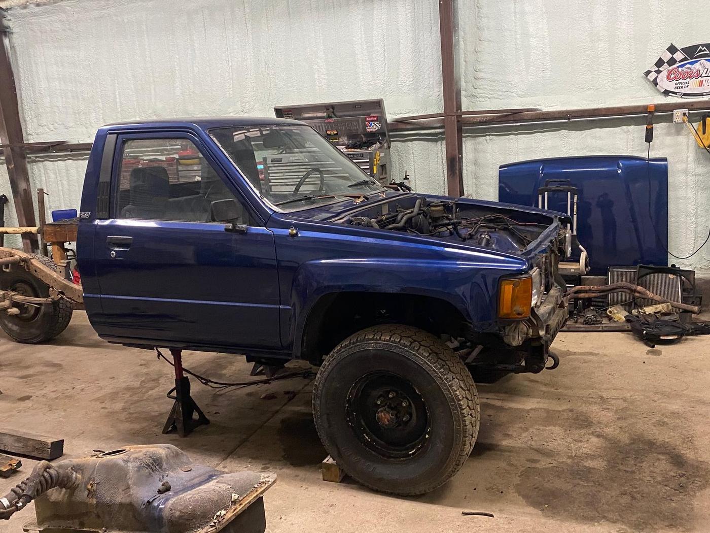 Blue Toyota 4x4 pickup mid-project in the shop with its hood off